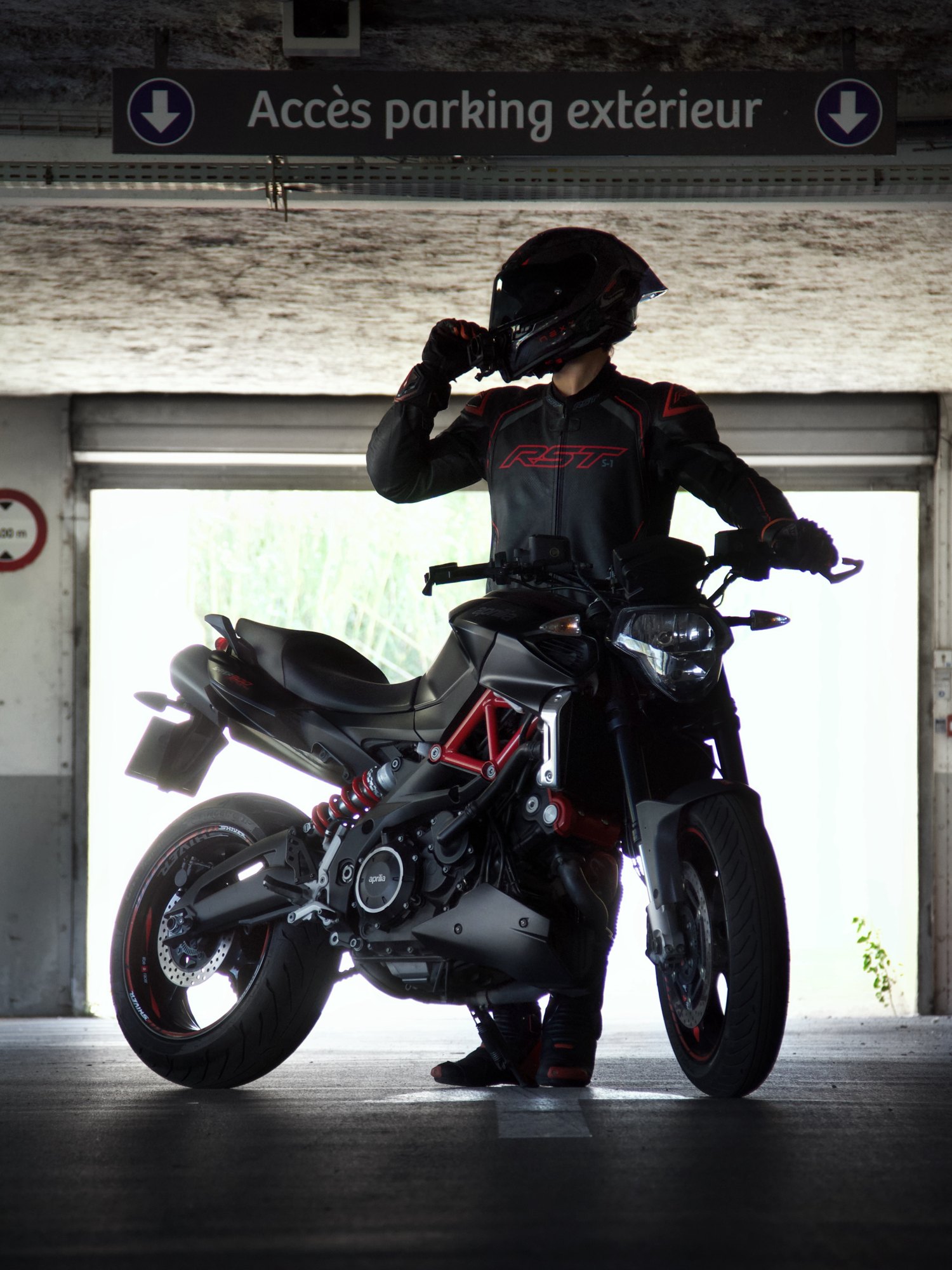 Motarde en contre-jour avec sa moto dans un parking – shooting moto